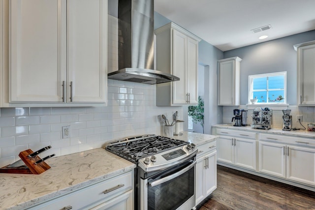 kitchen with visible vents, dark wood-type flooring, gas stove, wall chimney exhaust hood, and white cabinets