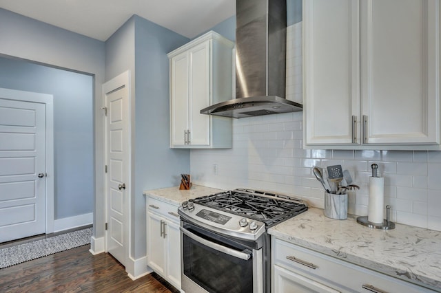 kitchen with stainless steel gas range oven, dark wood-type flooring, white cabinetry, wall chimney range hood, and decorative backsplash