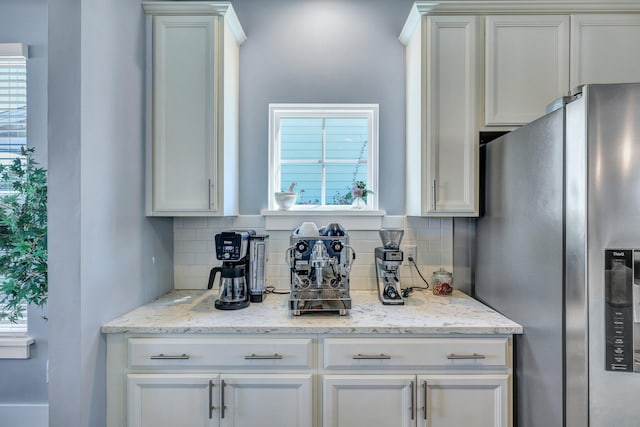 kitchen featuring plenty of natural light, stainless steel refrigerator with ice dispenser, and backsplash