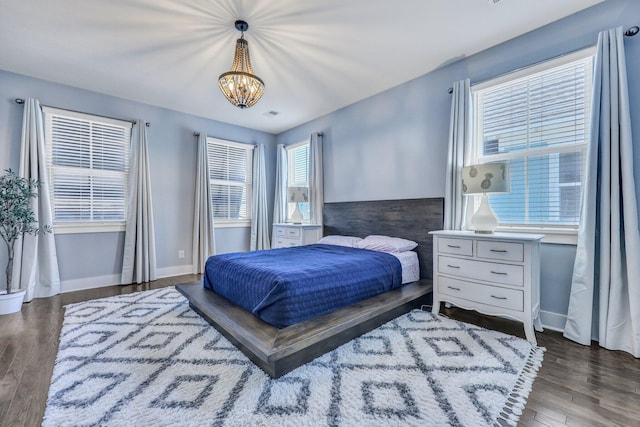 bedroom featuring a notable chandelier, baseboards, and wood finished floors