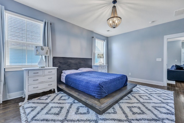 bedroom with dark wood-style floors, visible vents, baseboards, and a notable chandelier
