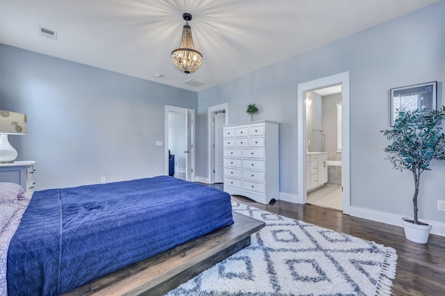 bedroom with wood finished floors, visible vents, baseboards, ensuite bath, and an inviting chandelier
