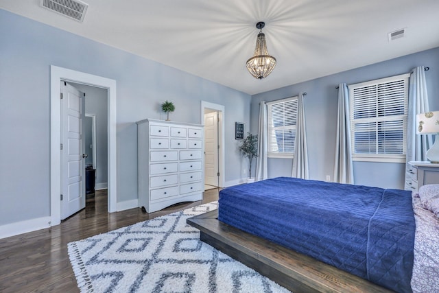 bedroom with visible vents, baseboards, a notable chandelier, and wood finished floors