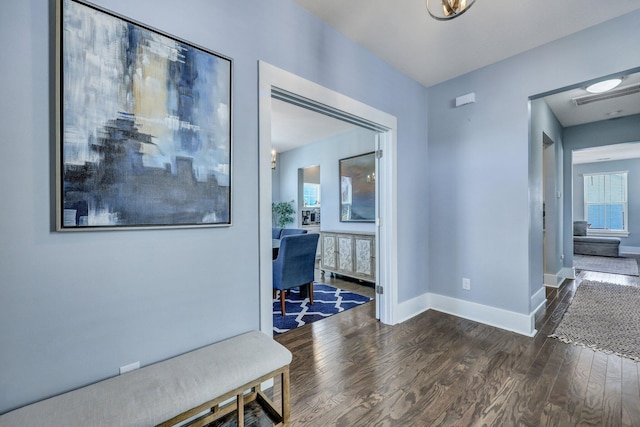 hall featuring dark wood-type flooring, visible vents, and baseboards