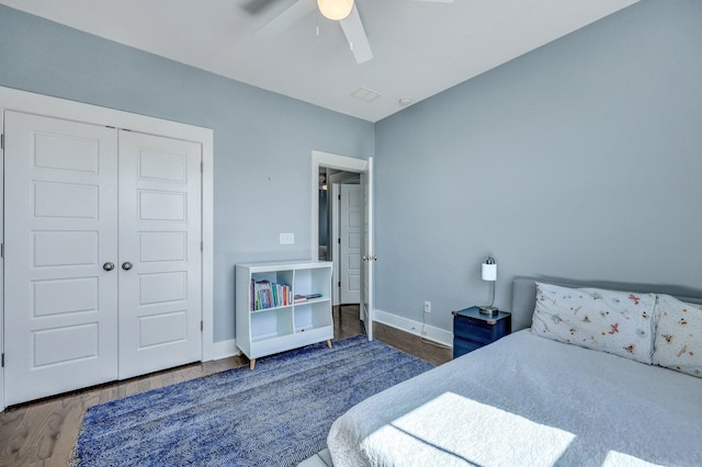 bedroom with a closet, a ceiling fan, baseboards, and wood finished floors