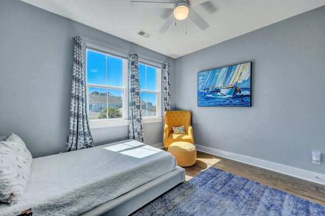 bedroom featuring visible vents, baseboards, wood finished floors, and a ceiling fan