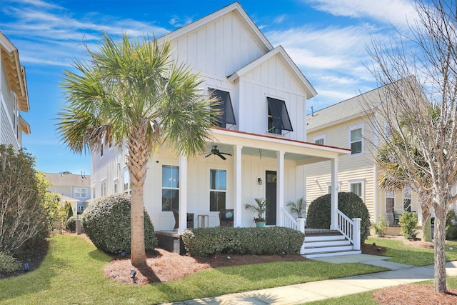 modern farmhouse style home with covered porch, board and batten siding, a front yard, and a ceiling fan