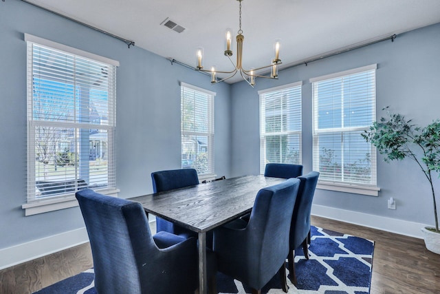 dining room with an inviting chandelier, wood finished floors, visible vents, and baseboards