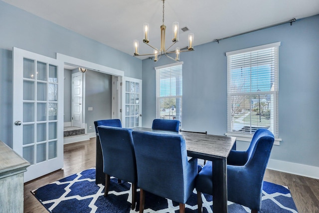 dining area featuring visible vents, baseboards, french doors, an inviting chandelier, and wood finished floors
