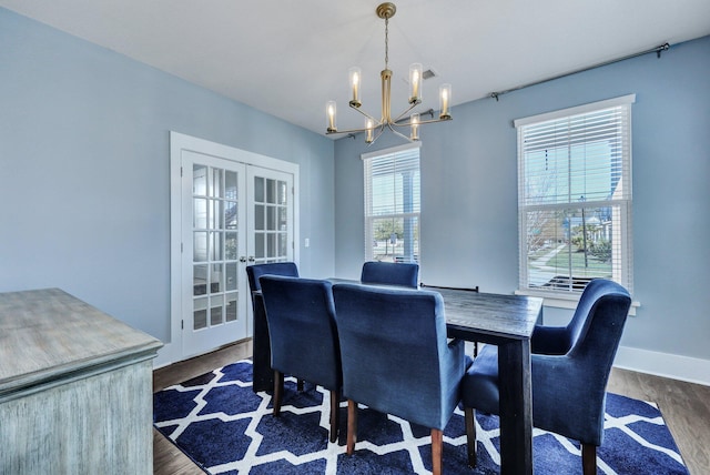 dining area with french doors, baseboards, dark wood-type flooring, and an inviting chandelier
