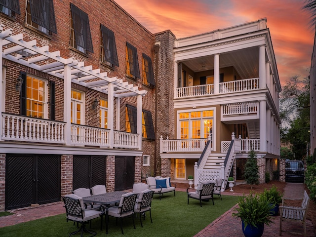 back house at dusk featuring a yard, an outdoor hangout area, and a pergola