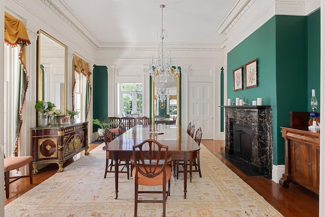 dining space with ornamental molding, hardwood / wood-style floors, a fireplace, and an inviting chandelier