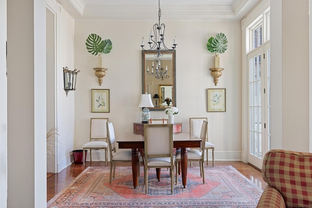 dining area featuring hardwood / wood-style floors, ornamental molding, and a chandelier