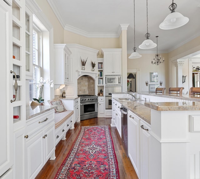 kitchen featuring white cabinets, stainless steel appliances, plenty of natural light, and decorative light fixtures