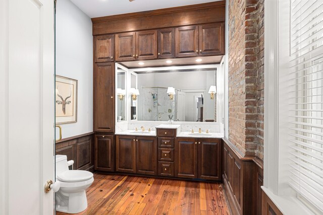 bathroom featuring toilet, hardwood / wood-style floors, wooden walls, vanity, and a shower with door