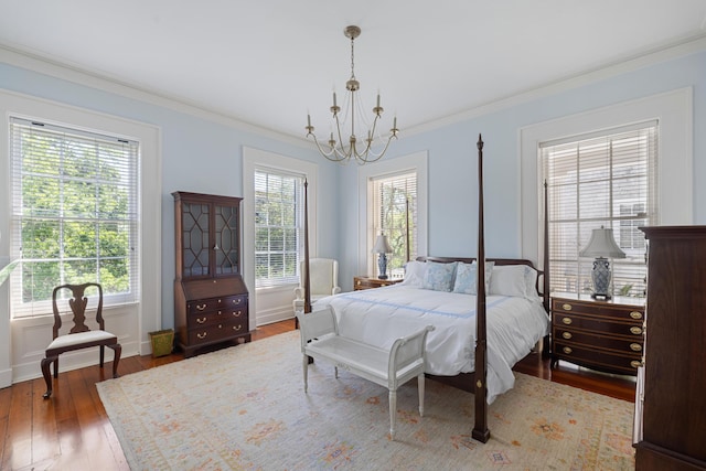 bedroom with multiple windows, wood-type flooring, ornamental molding, and a chandelier