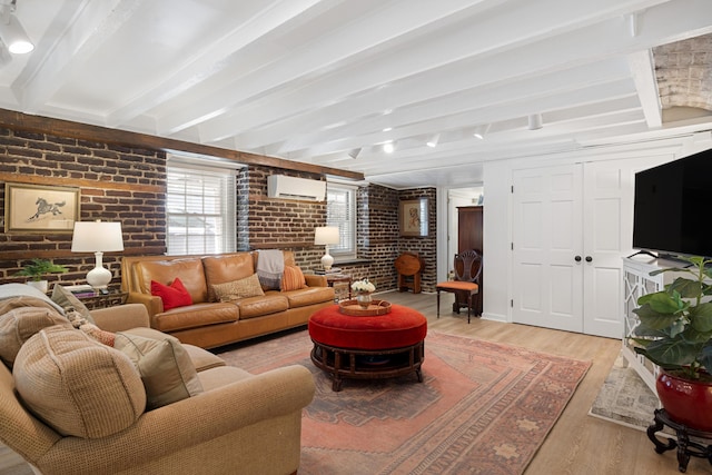 living room featuring brick wall, a wall mounted AC, beamed ceiling, and light wood-type flooring