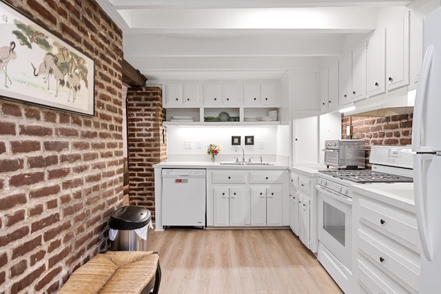 kitchen featuring brick wall, white appliances, white cabinets, beamed ceiling, and sink