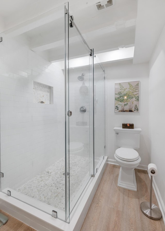 bathroom featuring hardwood / wood-style floors, toilet, and walk in shower