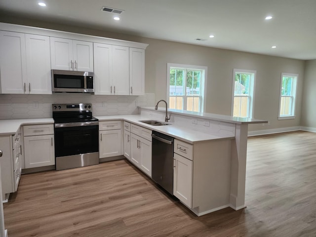 1207 Albert Storm Ave, Moncks Corner, SC 29461 - kitchen with stainless steel appliances, a sink, a peninsula, light wood finished floors, and recessed lighting