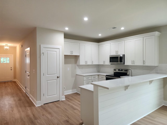 1207 Albert Storm Ave, Moncks Corner, SC 29461 - kitchen with electric range oven, stainless steel microwave, a peninsula, light wood-type flooring, and recessed lighting