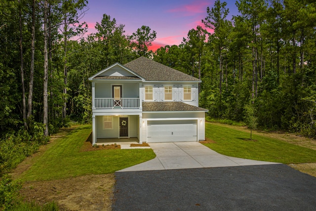 view of front of house with a yard, a garage, and a porch