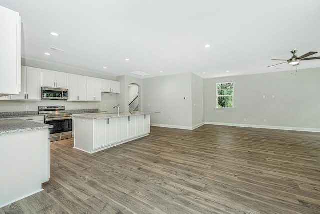 kitchen featuring white cabinets, an island with sink, appliances with stainless steel finishes, wood-type flooring, and sink