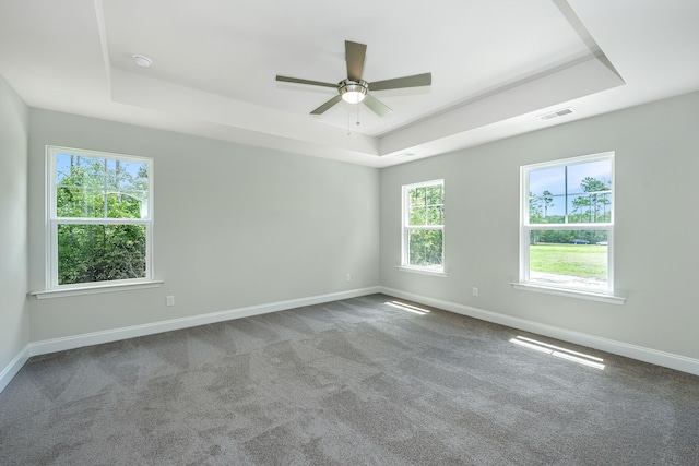 carpeted empty room with a tray ceiling and ceiling fan