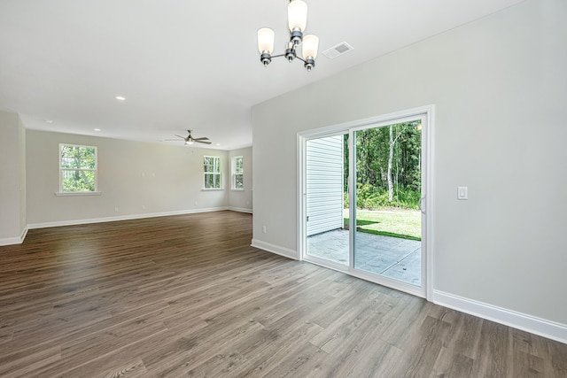 unfurnished living room with hardwood / wood-style flooring, ceiling fan with notable chandelier, and a wealth of natural light