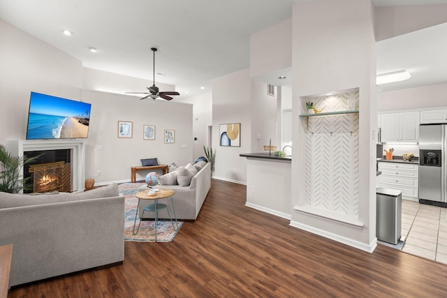 living room with dark hardwood / wood-style floors, ceiling fan, and high vaulted ceiling