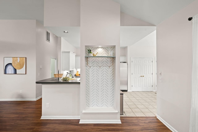 kitchen featuring white cabinets, sink, dark hardwood / wood-style floors, a towering ceiling, and kitchen peninsula