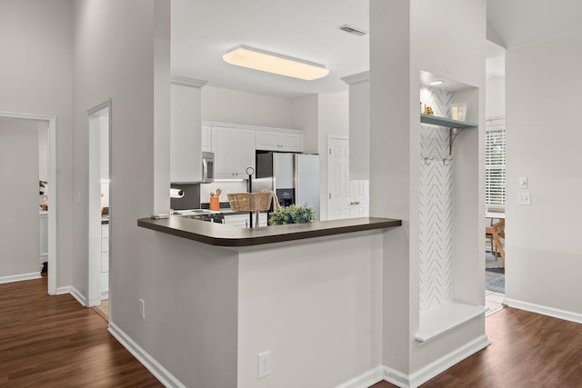 kitchen with kitchen peninsula, white cabinetry, dark hardwood / wood-style flooring, and appliances with stainless steel finishes