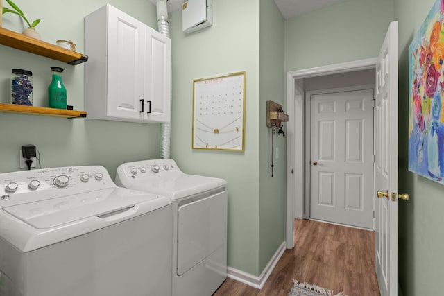 laundry area featuring washer and dryer, hardwood / wood-style floors, a wall unit AC, and cabinets