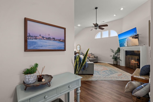 living room with ceiling fan, lofted ceiling, and dark wood-type flooring