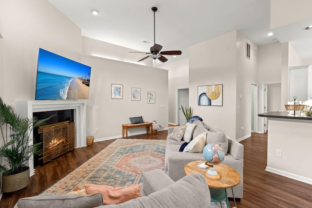 living room featuring dark hardwood / wood-style floors, ceiling fan, and a high ceiling