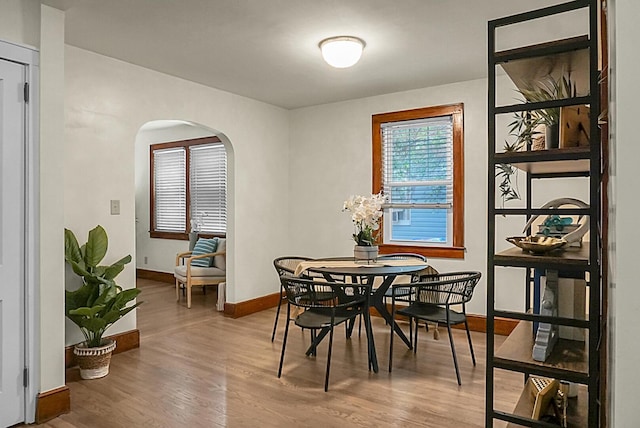 dining room with arched walkways, wood finished floors, and baseboards