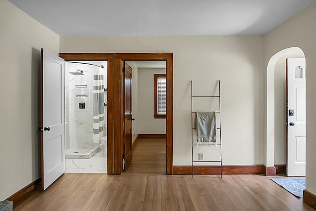 foyer entrance with arched walkways, wood finished floors, and baseboards