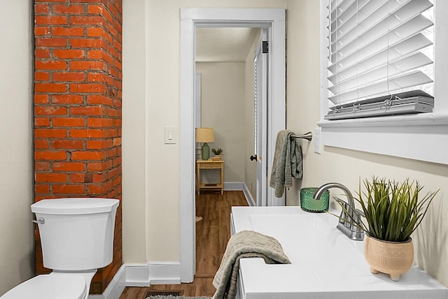 bathroom with wood finished floors, toilet, and baseboards
