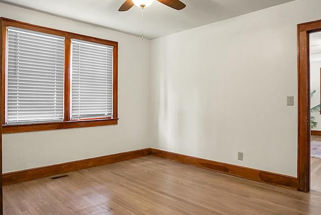 empty room with wood finished floors, a ceiling fan, and baseboards