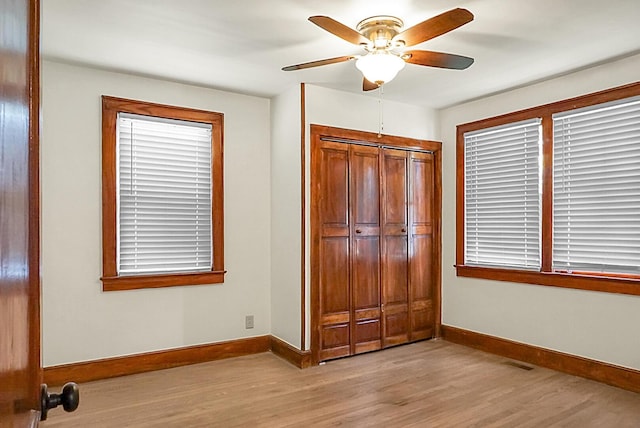unfurnished bedroom featuring baseboards, light wood-type flooring, a closet, and ceiling fan