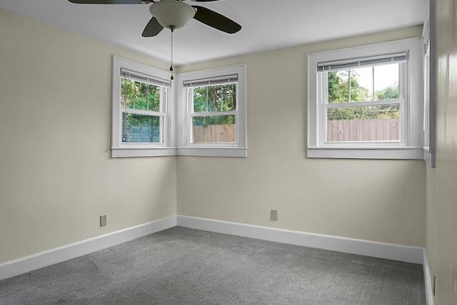 carpeted spare room featuring baseboards and a ceiling fan