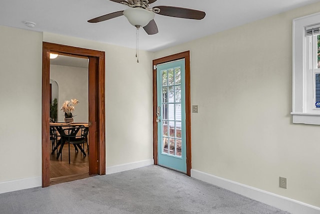 empty room featuring carpet floors, baseboards, a ceiling fan, and a smoke detector