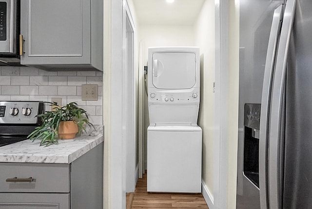laundry room featuring stacked washer / drying machine and wood finished floors