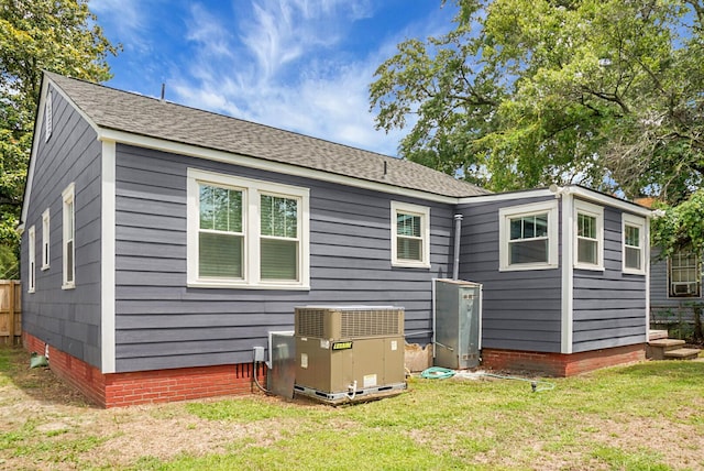 rear view of property with central AC unit, a lawn, and crawl space