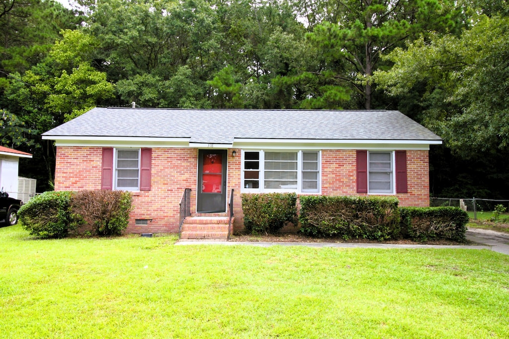 single story home with entry steps, a front lawn, and brick siding
