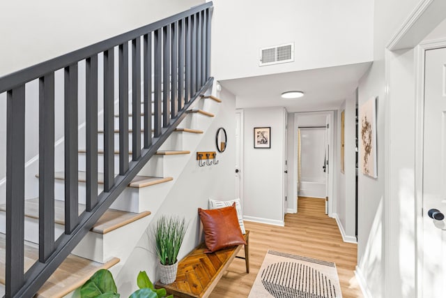 stairway with heating unit, visible vents, baseboards, and wood finished floors