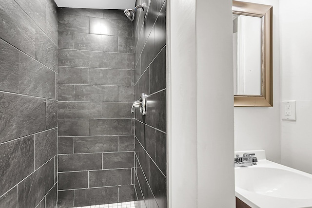 bathroom featuring tiled shower and vanity