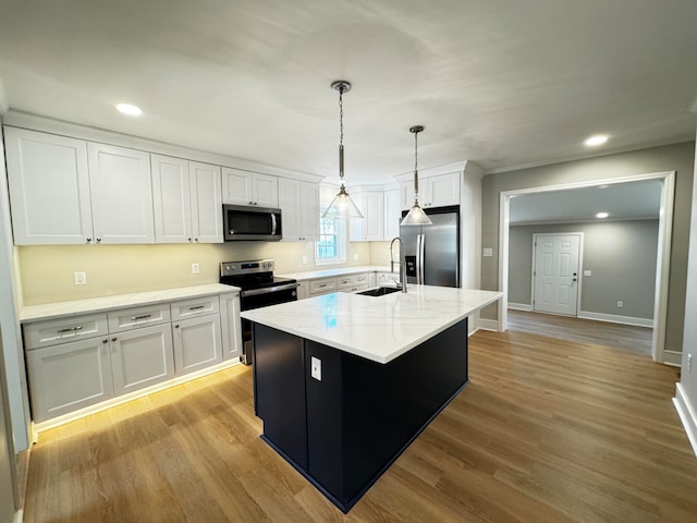 kitchen with white cabinets, appliances with stainless steel finishes, light hardwood / wood-style floors, and a center island with sink