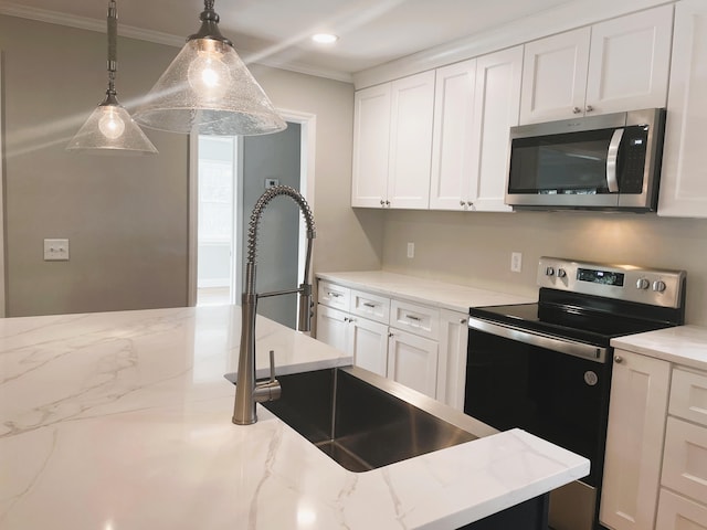 kitchen with appliances with stainless steel finishes, hanging light fixtures, ornamental molding, and white cabinetry