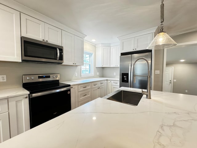 kitchen with hanging light fixtures, appliances with stainless steel finishes, white cabinets, light stone counters, and ornamental molding